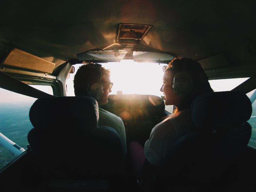 Two pilots in a cockpit flying during sunrise, experiencing adventure and travel.