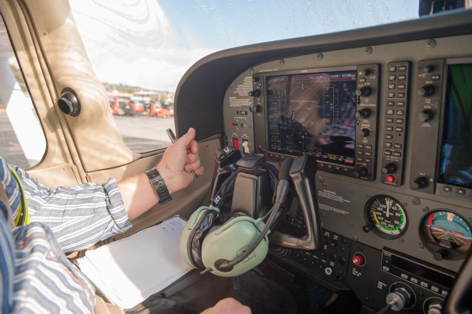 Close-up of a pilot navigating aircraft controls with modern avionics in a small plane cockpit.